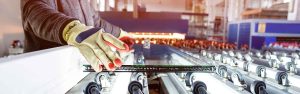 factory workers hands on a window which is on a conveyor belt