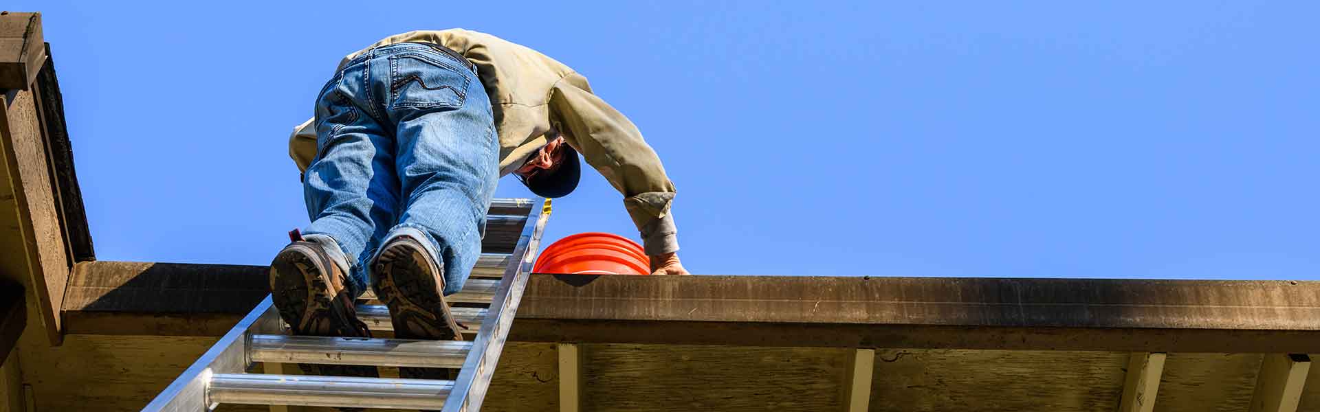 elderly man on high ladder cleaning gutters